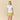 Woman wearing a white shirt and yellow patterned skirt on a beige background